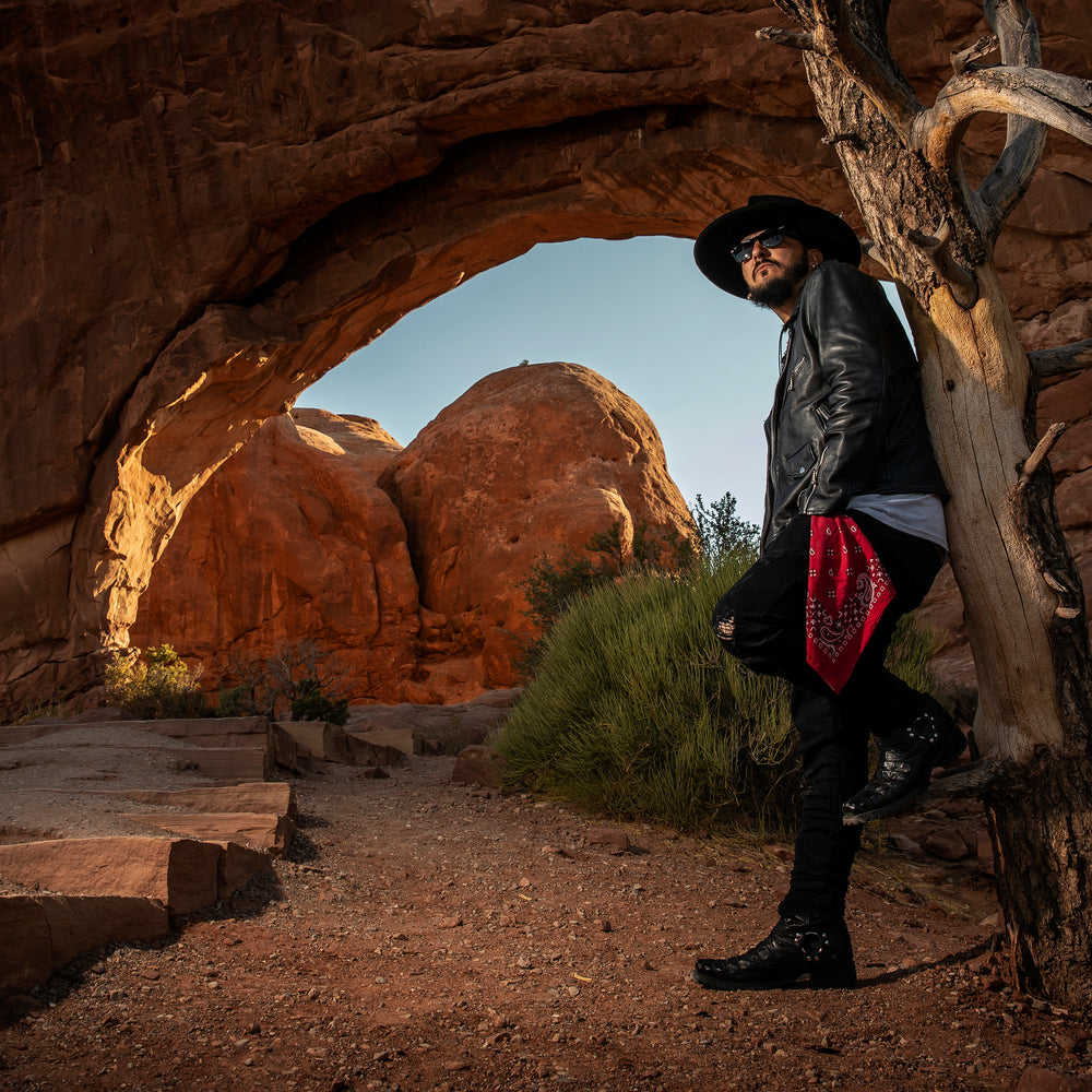 Singer Crucifix standing against a dead tree at the Windows Arch in Arches National Park Utah. SaintCruce