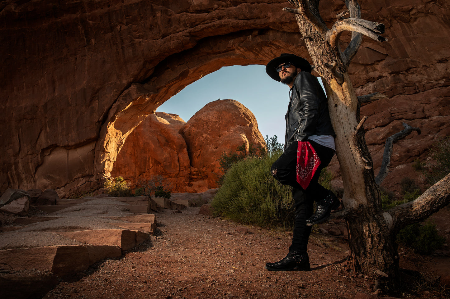 Singer Crucifix standing against a dead tree at the Windows Arch in Arches National Park Utah. SaintCruce